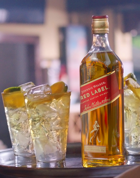 Johnnie Walker Red Label em uma bandeija com dois copos servidos com gelo, whisky e lascas de laranja