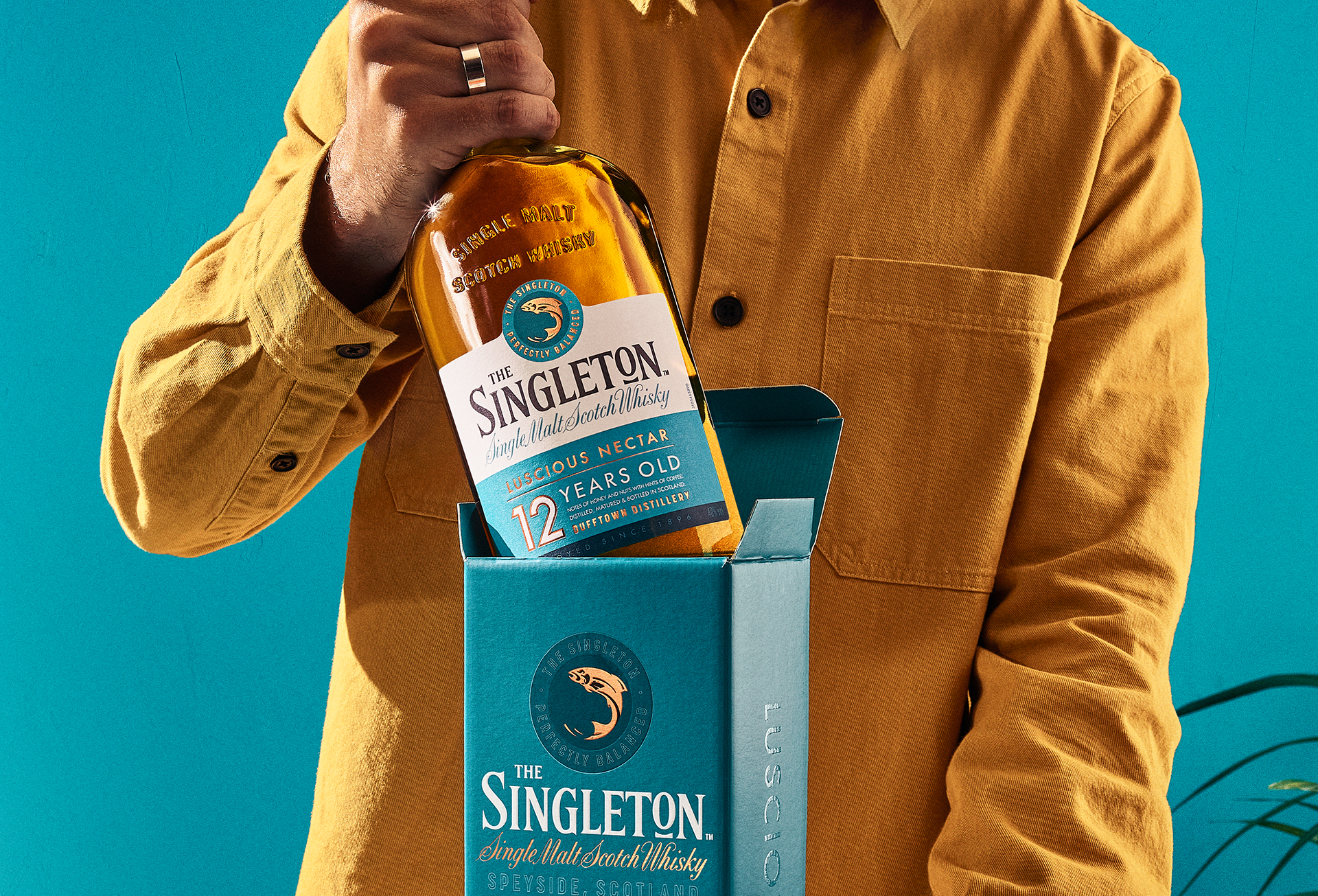 Um rapaz segurando a garrafa do whisky Singleton Of dufftown 12 anos 750ml.