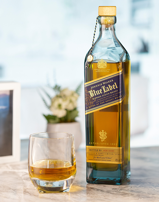 Garrafa do whisky Johnnie Walker Blue Label ao lado de copo com dose