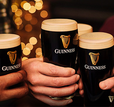 Mãos segurando copos da cerveja Guinness  