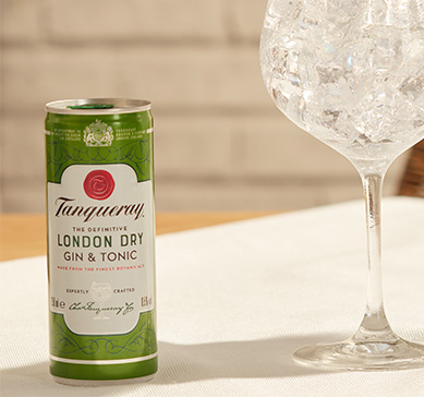 Tanqueray London Dry Tonic  269ml sobre a mesa ao lado de uma taça
