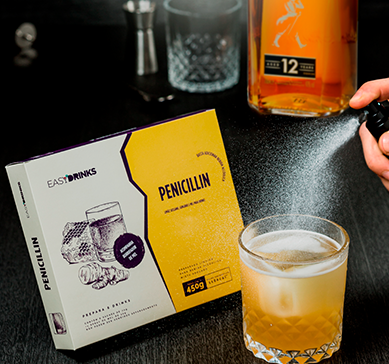 Garrafa de JW Black Label com um copo baixo de wisky e item Easy Drinks - Penicillin sobre a mesa.