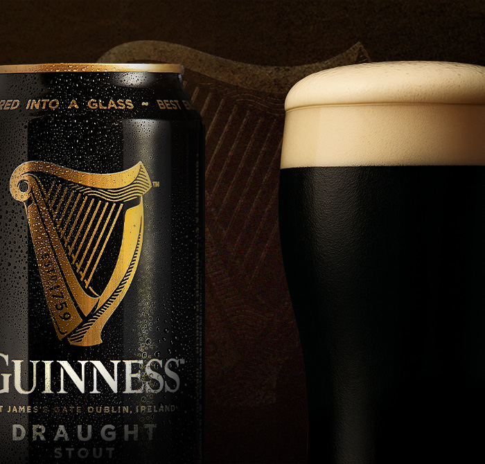 lata de cerveja Guinness Draught ao lado de copo de cerveja guinness com espuma
