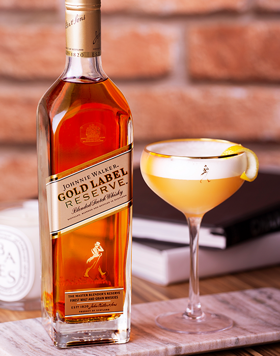 Garrafa do whisky Johnnie Walker Gold Label Reserve ao lado de copo com drink