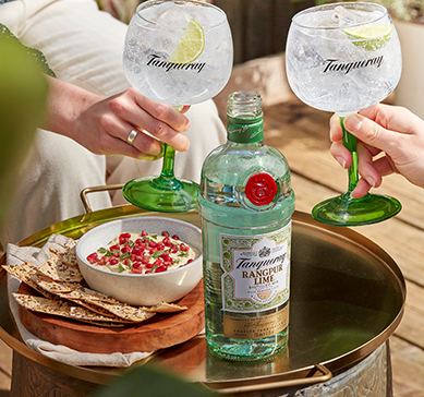 Garrafa de gin Tanqueray Rangpur e duas taças com drink brindando