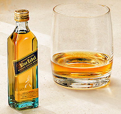 Mini Whisky Johnnie Walker Blue Label ao lado de copo om dose