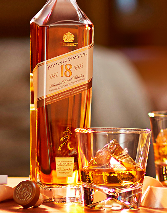 Garrafa do whisky Johnnie Walker 18 anos ao lado de copo com dose